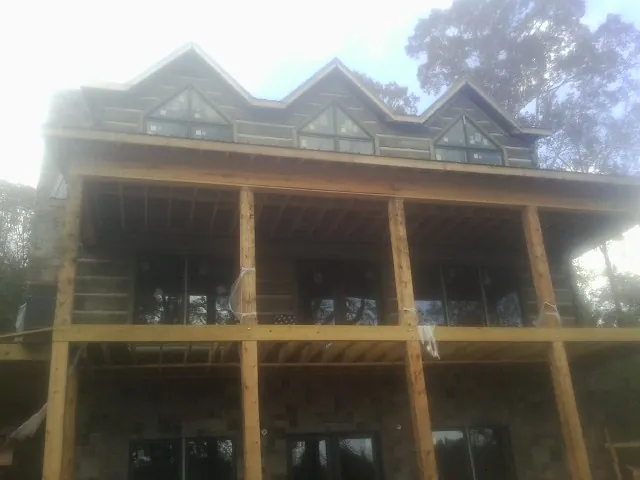 Dormers and porch framing on a large log home under construction — Roof Coating work by our crew in West Sand Lake