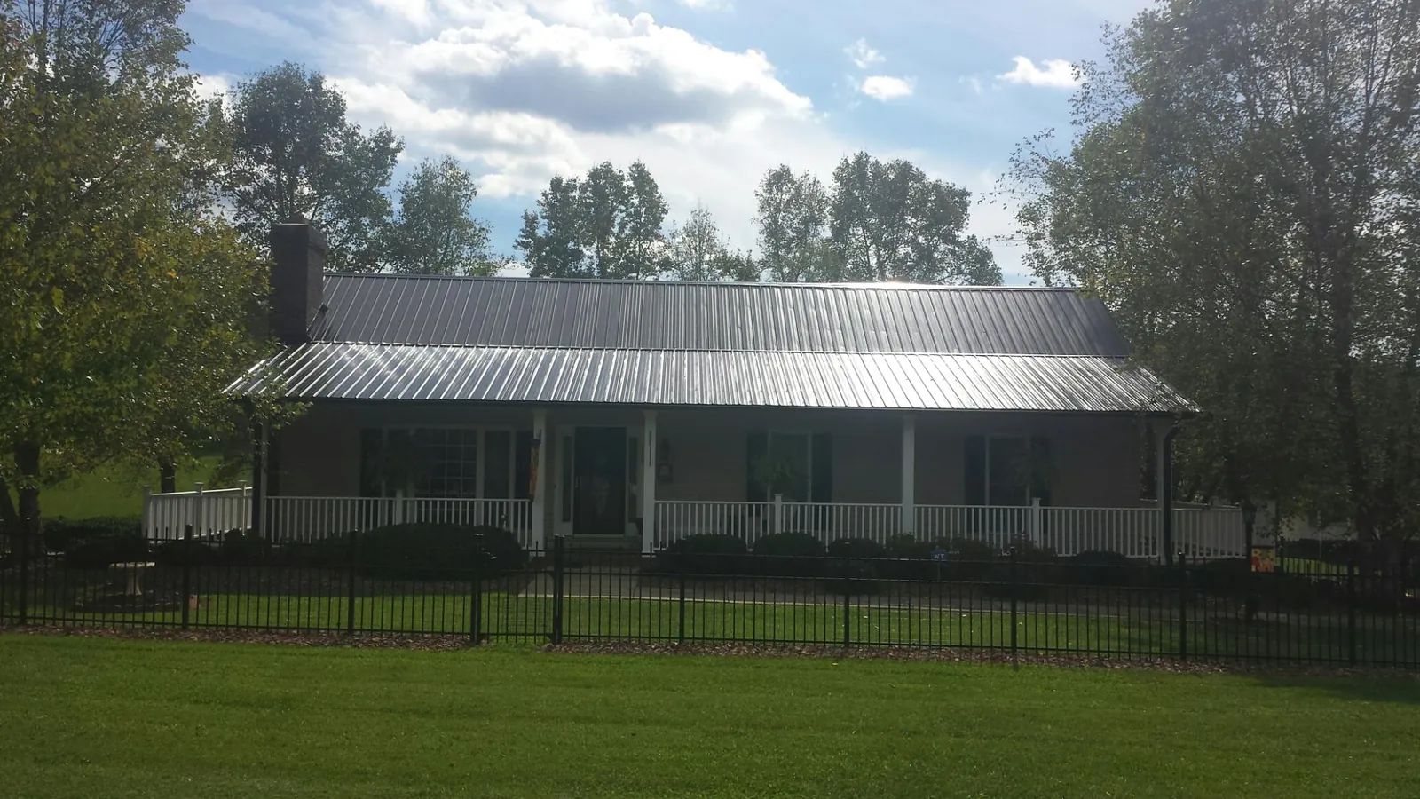 Gray metal roof on a brick ranch with a full width front porch — Gutter Guard Installation work by our crew in West Sand Lake