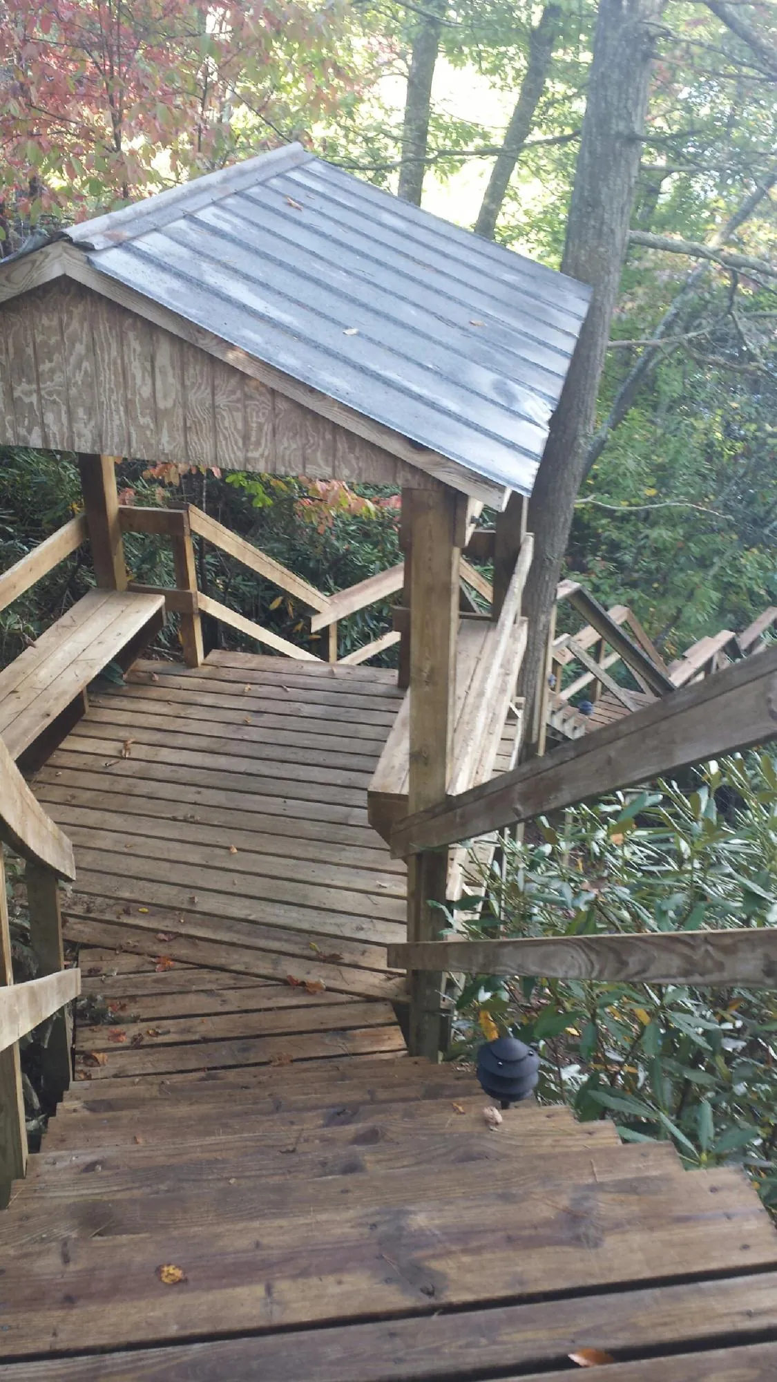 Metal roofed shelter over wooden steps on a wooded walkway — Skylight Repair & Installation work by our crew in West Sand Lake
