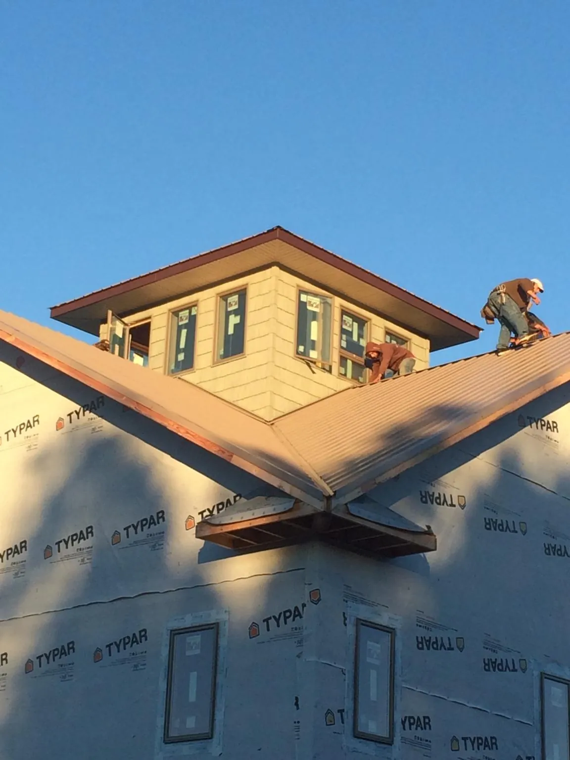 Roofers working around a rooftop cupola on a new metal roof at sunset — Roof Waterproofing in West Sand Lake by Roofing Brothers